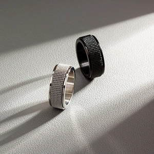 Detailed view of 8mm rotating rings with metal mesh texture on grey leather background