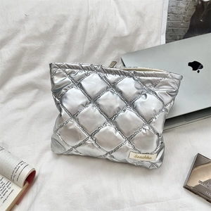 Quilted silver heart cosmetic bag with zipper and logo detail on white fabric background