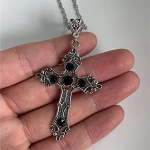 Vintage silver Gothic cross necklace with black gemstone inlay held in hand on white background