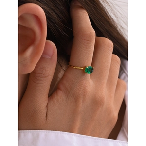 Detailed view of an 18k gold stainless steel ring with a green zircon stone on a finger
