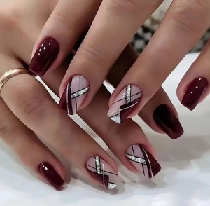 Macro view of burgundy and nude press-on nails with silver glitter geometric lines