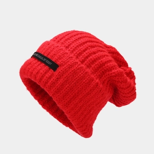Detalle del tejido de punto rojo del gorro y parche de tela negro con letras blancas