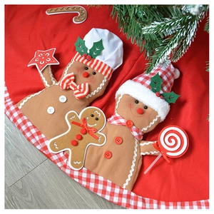 Detailed embroidery of gingerbread men on a red plush Christmas tree skirt with plaid border