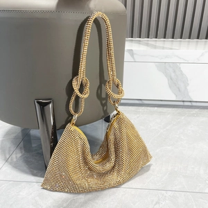 Close-up of golden rhinestone handbag featuring a knotted strap detail and crystal finish