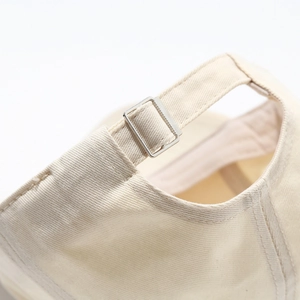 Close-up of beige cotton baseball cap back with silver metal adjustable buckle