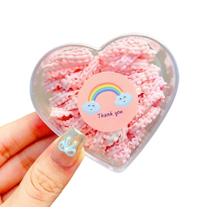 Pink ruffled elastic hair ties for girls in a heart-shaped box with rainbow stickers