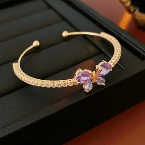Détail du bracelet papillon doré avec pierres de zircon violettes sur cuir noir