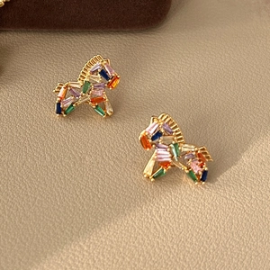 Detailed macro view of gold-plated horse earrings with vibrant multi-colored gemstones