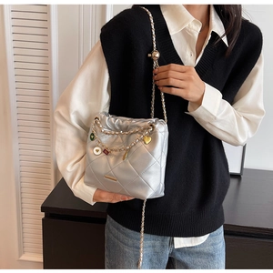 Detail of silver quilted bucket bag featuring a gold chain strap and heart charms