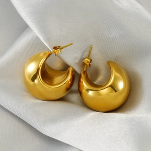 Detailed view of chunky golden crescent moon earrings on a soft grey silk background