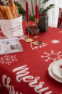 Close-up of red Christmas tablecloth with white snowflake prints and festive text