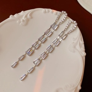 Macro view of silver U-shaped tassel earrings with pavé zircons and trapezoid cut gems