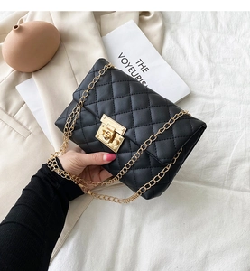 Detail of black quilted leather shoulder bag with gold chain strap and metal lock