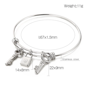 Detail view of stainless steel lock and key charms with dimensions on a bangle