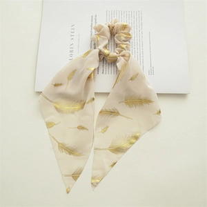 Detail of chiffon scrunchie with long ribbons and elegant gold feather patterns