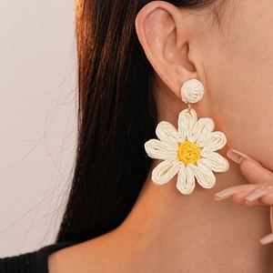 Handwoven daisy flower earrings with white petals and yellow center on a model