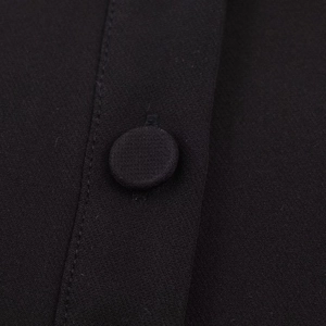 Détail du bouton recouvert de tissu et coutures de précision sur le haut polo noir
