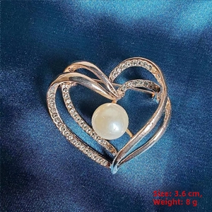 Detail of rose gold double heart brooch with sparkling rhinestones and center pearl