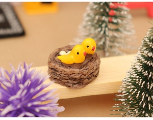 Detailed view of a resin miniature bird nest with two yellow birds and eggs