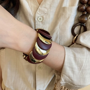 Detailed close-up of chunky gold moon-shaped link bracelet with burgundy matte resin inlay