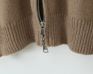 Macro detail of brown knit cardigan featuring double metal zippers and ribbed hem finish