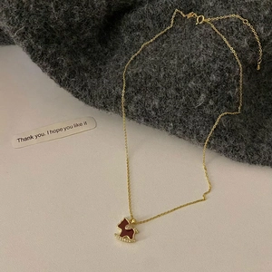 Macro view of 18K gold plated horse necklace with red pendant and zircon accents