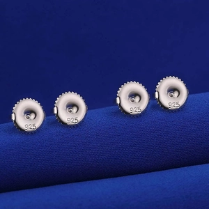 Detail view of 925 sterling silver ear nut backings on a blue textured background