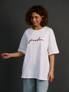 Oversized λευκό βαμβακερό T-shirt με μπορντό τύπωμα freedom σε γκρι φόντο υψηλής αντίθεσης