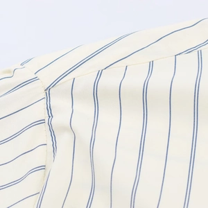 Detailed close-up showing the precise stitching and blue stripes on the cream shirt fabric
