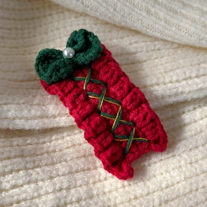 Macro shot of a red and green hand-knitted Christmas tree hair clip with a pearl detail