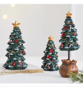 Close-up of mini resin Christmas trees with gold stars and festive red ornaments