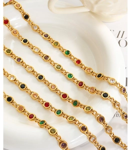 Detail of gold chain necklace with multi-colored zircon stones on white ceramic decor