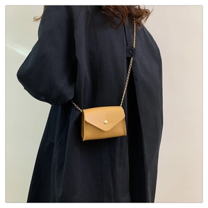 Detailed view of ginger yellow crocodile textured small square bag with gold chain strap