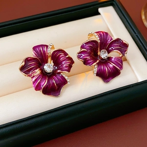 Detailed macro of purple flower earrings with gold edges and sparkling crystals