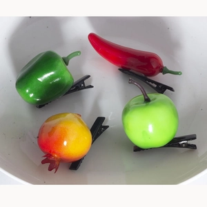 Detailed view of realistic resin fruit hair clips featuring chili and apple designs