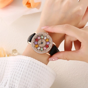 Ladies rose gold rhinestone watch with flower dial and black leather strap worn on wrist