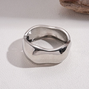 Macro shot of silver wide metal bangle with irregular organic wave shape and mirror finish