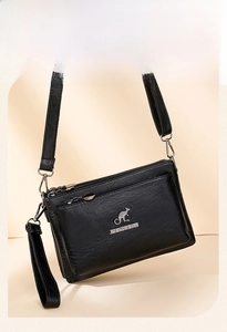 Detalle del bolso bandolera de cuero negro con tres compartimentos con cremallera metálica