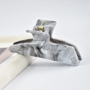 Close-up of a grey marble pattern acetate hair claw clip with golden metal spring