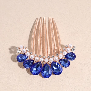 Detail view of golden hair comb with blue crystal teardrops, white pearls and clear rhinestones