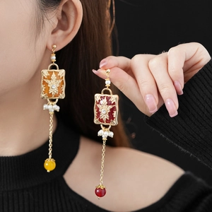 Detail of vintage gold earrings with rhinestones, pearls and long colorful tassels