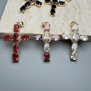 Colorful zircon cross pendants in gold plating displayed on stone surface