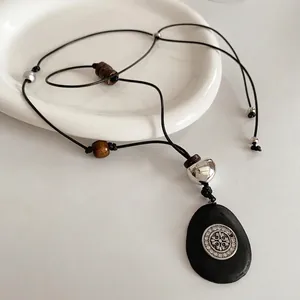 Collier ethnique avec pendentif en bois et strass sur une assiette blanche