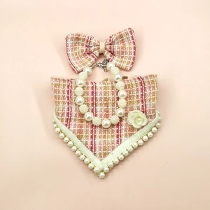 Detail of pink tweed dog bandana with matching bow and pearl necklace accessory
