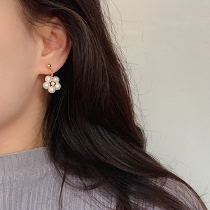 Detail view of pearl flower stud earrings worn on ear with elegant gold center bead