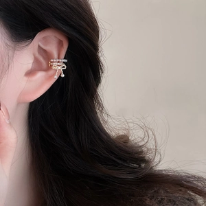 Elegant gold bow ear cuff featuring white pearls and zircon crystals on model