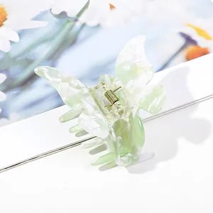 Macro detail of marble green butterfly hair claw clip with golden spring and acetate finish