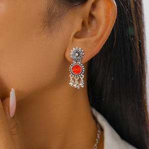 Close-up of vintage silver floral earrings with red stones and tassels on model