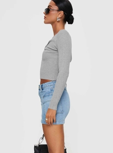 Vue latérale d'une mini-jupe en jean délavé avec un haut court gris à manches longues