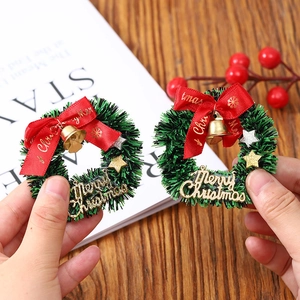 Mini Christmas star wreath with golden bell and red ribbon bow on green pine needles